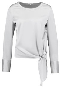 Lichtgrijze blouse met lange mouwen van gladde stof, met een ronde halslijn en een strikdetail in de taille, voorzien van satijnen manchetten.