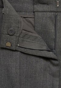 Tissu en mélange de laine gris avec un subtil motif en chevron. Présente une poche à bouton et zippée, ainsi qu'une doublure lisse pour une fonctionnalité accrue.