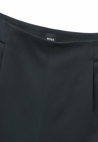 Musta kangashame, jossa on sileä pinta, BOSS-tunnus, laskokset ja muotoiltu malli. Korkea vyötärö ja siisti viimeistely.