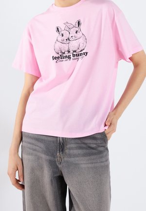 Różowa bawełniana koszulka z grafiką dwóch królików i napisem poniżej; krótki rękawek i swobodny fason.