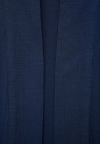 Marinblå, lättviktig tyg med en texturerad yta. Öppen frontdesign utan stängningar, med rena linjer och minimal detaljer.