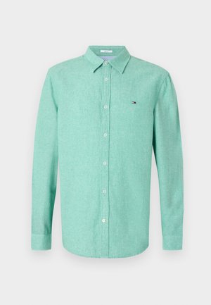 Svetlo zelena srajca z dolgimi rokavi iz teksturirane tkanine. Ima ovratnik z gumbi, sprednje gumbe in majhno logotip na levi strani prsnega koša.