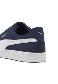 Mørkeblå sneakers med hvide læderdetaljer, struktureret stof, rund form og en hvid gummisål. Guld logo detalje nær hælen.