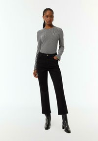 Black flared pants paired with a fitted black-and-white striped long-sleeve top. The top features ribbed texture and a round neckline.