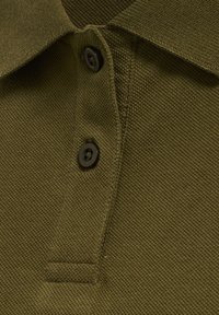 Kołnierz koszulki polo w oliwkowym kolorze z fakturą, z dwoma ciemnymi guzikami przyszytymi na listwie zapinającej.
