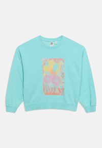 Sweatshirt bleu clair à manches longues, poignets et ourlet côtelés, avec un imprimé floral rose et jaune et le texte « Roxy ».
