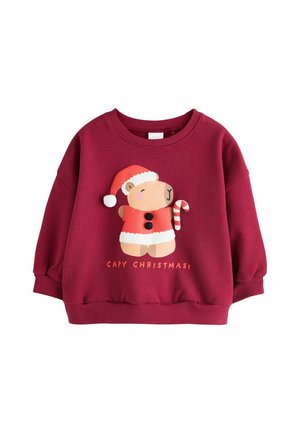 Červený vianočný sveter pre deti s medveďom nosiacim čiapku a plášť Mikuláša držiacim cukrík so textom "CAPY CHRISTMAS".