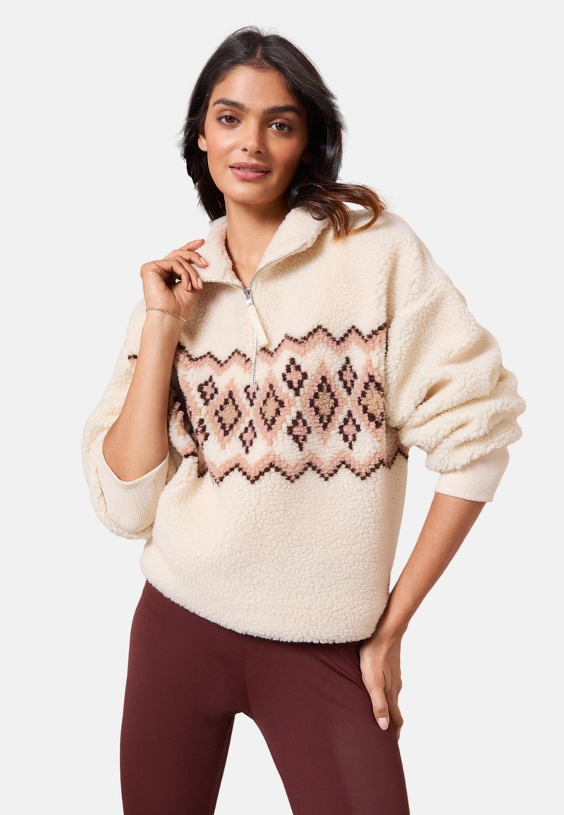 Pulover din fleece de culoare crem cu guler cu jumătate de fermoar, având un model geometric în nuanțe de roz și maro pe piept. Textură moale, croială lejeră.