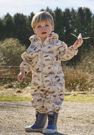 Waterdicht kinderpak in beige met ruimte-thema print, voorzien van een ritssluiting aan de voorkant, elastische manchetten en gecombineerd met blauwe rubberen laarzen.
