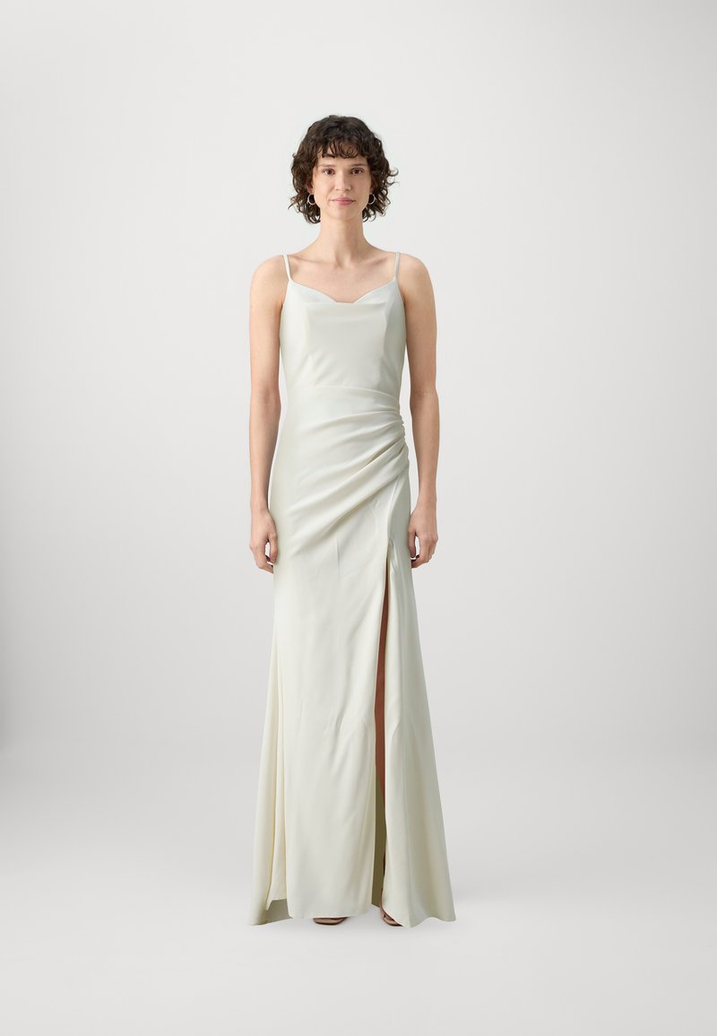 Robe de soirée longue sans manches en satin crème clair. Présente un corsage ajusté, un drapé sur le côté et une fente haute sur la cuisse.