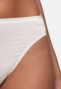 Culotte en coton blanc avec une taille élastique douce, présentant un design de coupe latérale et un branding minimaliste sur la hanche.