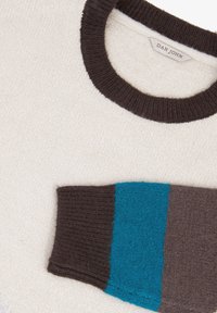 Maglione crema con un colletto a coste marrone scuro, dotato di una manica a strisce marrone e turchese testurizzata. Realizzato in materiale morbido e lavorato a maglia.