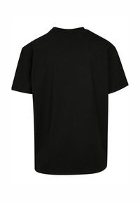 Camiseta de algodón negra con cuello redondo y mangas cortas. La parte posterior presenta una superficie lisa y sólida sin logotipos ni patrones.