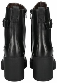 Sorte læder ankelstøvler har en blokhæle, sidezipper og justerbare stropper med metalliske spænder. Glat tekstur og elegant design.