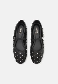 Black leather Mary Jane flats featuring silver stud accents, round toe, adjustable strap, and smooth interior lining.