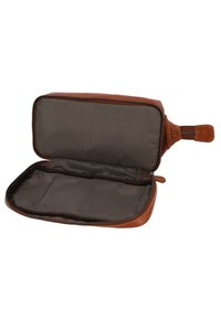 Bruine leren toilettas met een ritssluiting, een leeg interieur met een gladde donkere voering en een zijhandvat om mee te dragen.