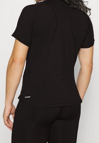 Černé sportovní tričko s krátkým rukávem, přiléhavým střihem a perforovanými detaily na zádech pro lepší prodyšnost.