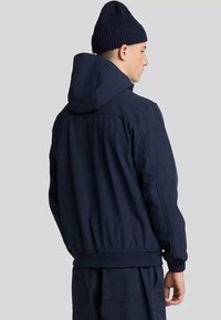 Giacca con cappuccio blu navy con polsini e orlo a costine, realizzata in un tessuto testurizzato e con una vestibilità rilassata e informale. Adatta per il tempo fresco.