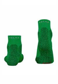 Un paio di calzini alla caviglia verde vivace con aree di grip rinforzate nere e logo "FALKE" in bianco sui polsini, mostrati da viste posteriori e della suola.