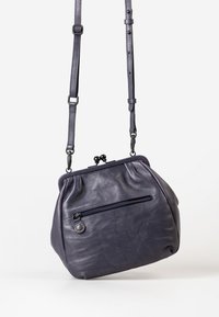 Borsa a tracolla in pelle viola con tracolla regolabile, forma arrotondata, chiusura a scatto superiore e tasca con zip sul retro. Texture liscia.
