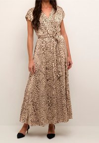 Maxi šaty v béžové barvě s leopardím vzorem, zavinovací design, krátké rukávy, s uvázaným pasem a splývavou sukní. V kombinaci s černými lodičkami.