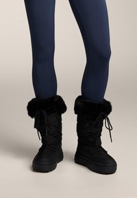 Čierne snehové čižmy s manžetami z umelého kožušiny, so šnurovaním, hrubou podrážkou a polstrovanou látkou pre teplo a pohodlie.