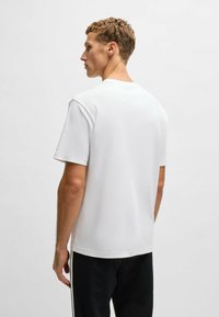 Hvid kortærmet t-shirt, rund halsudskæring, lavet af blød bomuld, enkel design, ingen mønstre, set fra ryggen.