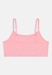 Rosa bomull bralette med justerbara band och en bred remsa med ordet "CONVERSE" i vit text längs botten.