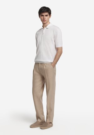 Ljusgrå pikétröja med korta ärmar, knappslå; beige linnebyxor med avslappnad passform; ljusbruna espadrillos med vävd kant.