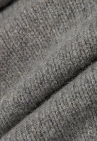 Graues gestricktes Material mit einer weichen, strukturierten Oberfläche. Hat ein geripptes Muster und ein leicht verschwommenes Aussehen.