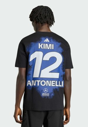 Osoba s krátkými dredy, která má na sobě černé tričko s modrým pozadím, číslo 12 a nápis „KIMI ANTONELLI“ na zádech.