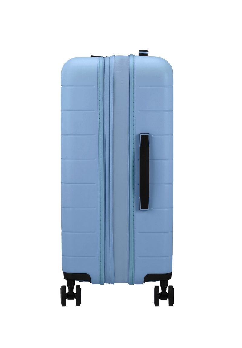 Valigia rigida blu chiaro con quattro ruote nere e una maniglia laterale nera, in piedi su uno sfondo bianco.