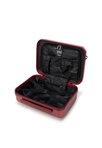 Tvrdý kufr v burgundské barvě s texturovaným povrchem. Interiér je vybaven černou podšívkou, popruhy na upevnění věcí a organizačními kapsami.