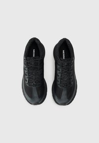 Des chaussures de sport noires avec une tige en tissu texturé, un design à lacets et des semelles en caoutchouc dotées d'un motif rayé subtil sur la zone des orteils.