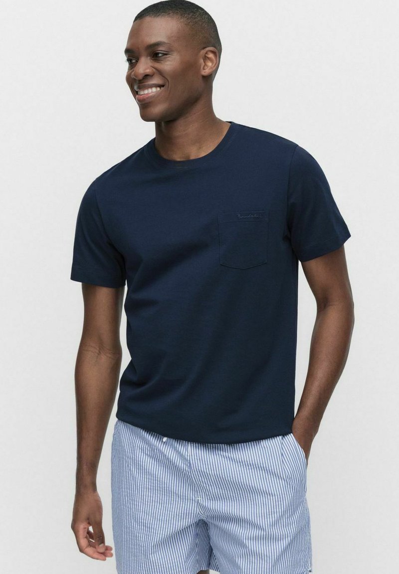 Marineblauwe T-shirt met korte mouwen en een borstzak, gemaakt van zachte stof, gecombineerd met lichtgestreepte shorts. Gladde textuur, normale pasvorm.