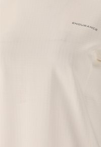 Hellbeige Sportshirt aus glattem Stoff. Verfügt über eine subtile Textur und das "ENDURANCE"-Logo in Grau auf der oberen rechten Seite.