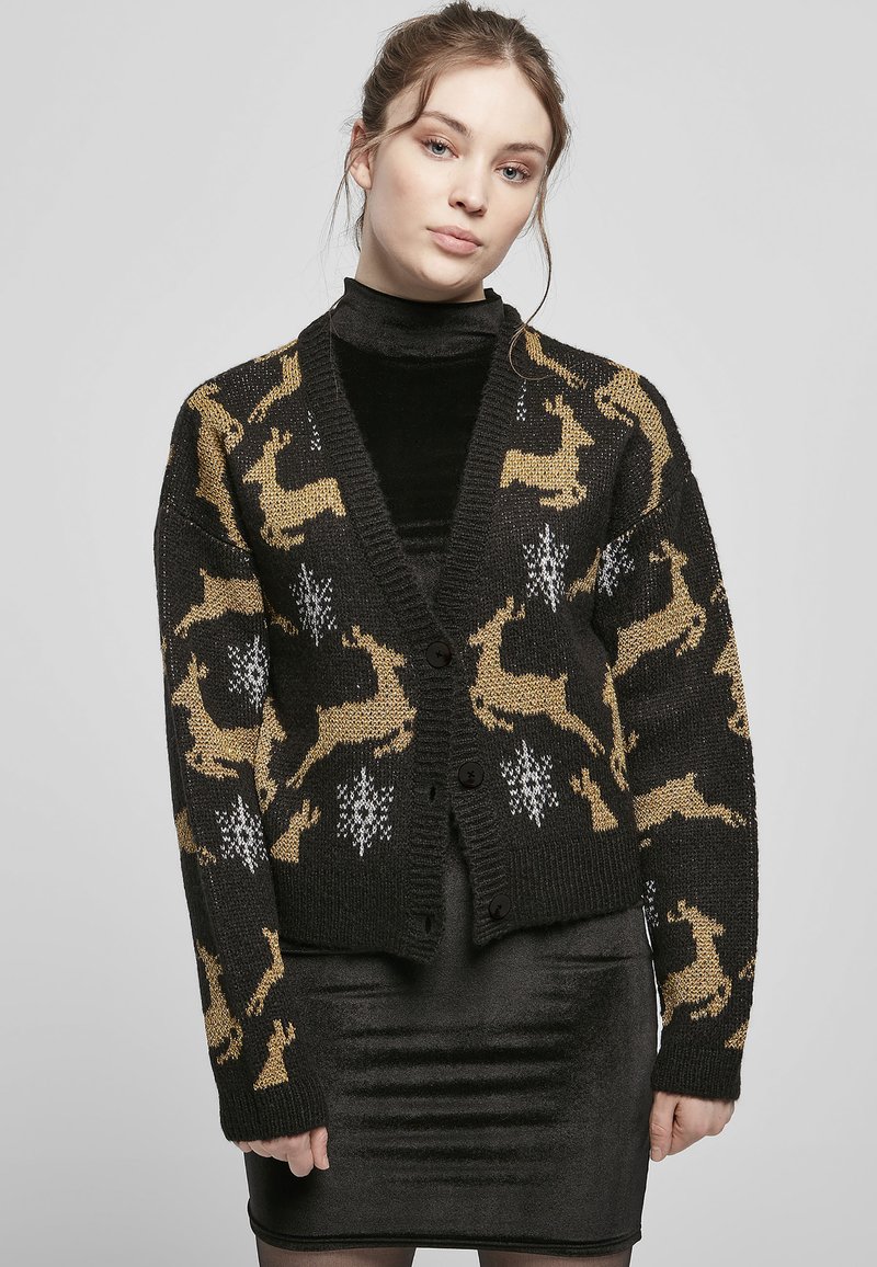 Black knitted cardigan featuring a gold reindeer pattern and white snowflakes, with a v-neckline and five black buttons.