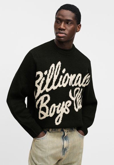 Μαύρο πλεκτό πουλόβερ με μεγάλο λευκό κείμενο "Billionaire Boys Club". Λαιμόκοψη με ριμπ μανσέτες. Συνδυάζεται με ανοιχτόχρωμο τζιν.