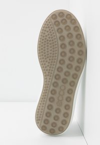 Podeszwa buta z okrągłymi wypustkami do przyczepności i mniejszymi teksturowanymi kropkami w beżowej gumie, z nazwą marki "ecco" wytłoczoną na środku.