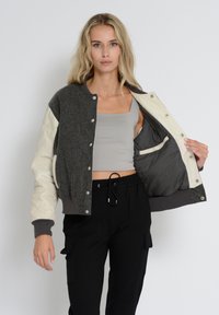 Grå uldblanding bomberjakke med cremefarvede quilted ærmer, trykknapper, ribbede manchetter og en kontrastgrå inderside.