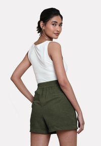 Hvid ærmeløs top parret med olivengrønne shorts med elastisk talje og to baglommer. Glat stof, afslappet pasform.