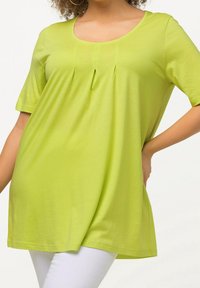 Limonengrünes Kurzarmoberteil mit einem runden Ausschnitt und vertikalen Falten an der Vorderseite. Hergestellt aus leichtem, glattem Stoff mit einer lockeren Passform.