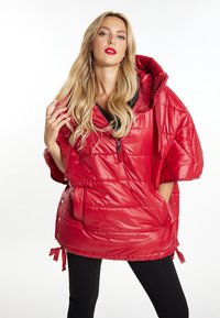 Rød puffer halv-zip jakke med en bred hætte, blank overflade, sidelommer og justerbare snore i kanten. Sort indvendig foret detalje.
