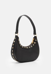 Svart läderhandväska med en böjd form, guldfärgade detaljer och dekorativa nitar i olika former längs ena sidan. Dragkedjeslutning upptill.