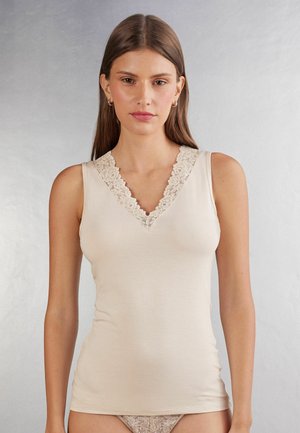 Top beige senza maniche con scollatura a V e bordi in pizzo sul collo. Realizzato in un tessuto morbido per una silhouette aderente.