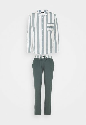 Gestreifte Button-up-Bluse mit grünen und weißen vertikalen Streifen; kombiniert mit dunkelgrünen Jogginghosen mit Kordelzug. Baumwollmaterial mit normaler Passform.