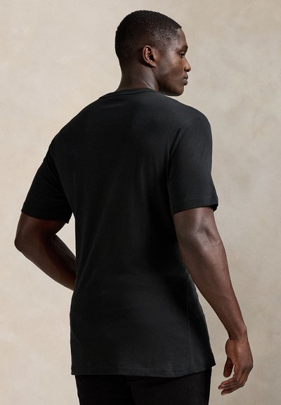 Černé tričko s krátkými rukávy z bavlny, s volným střihem, kulatým výstřihem a mírně prodlouženým zadním lemem.