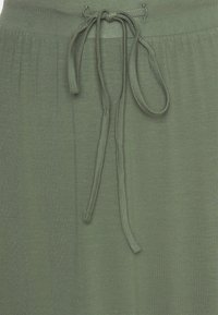 Olivgrön stickad kjol med dragsko i midjan, mjuk textur och subtila veck för en avslappnad passform. Minimalistisk design, utan mönster eller detaljer.