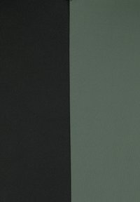 Zwei Stoffpaneele: eines schwarz, das andere olivgrün. Beide sind glatt mit einer subtilen gerippten Textur und entlang einer vertikalen Naht verbunden.