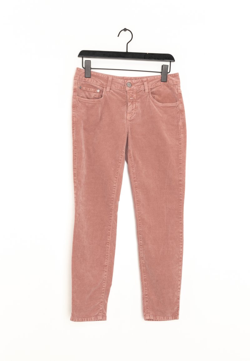 Pantalon slim en velours côtelé rose suspendu à un cintre noir sur fond blanc.